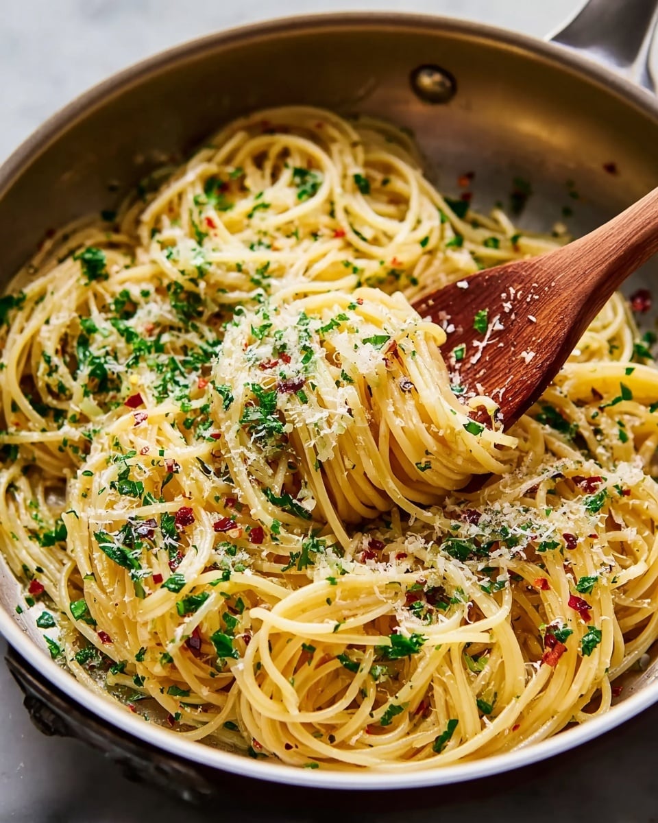 A close-up view of a pan filled with cooked spaghetti, twirled around a wooden spoon held by a woman's hand. The spaghetti is coated lightly in oil, making it shiny and smooth, sprinkled with fresh chopped green herbs and small bits of red chili flakes. On top, there is a generous layer of finely grated white cheese, adding a soft texture and pale color contrast. The background features a white marbled texture, highlighting the warm tones of the pasta and the deep brown of the wooden spoon. Photo taken with an iphone --ar 4:5 --v 7